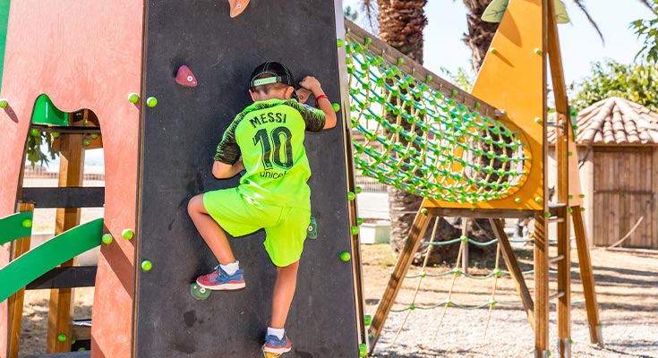 enfant sur le mur d'escalade de l'aire de jeux